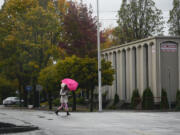 A woman tries to stay dry while crossing Main Street in downtown Vancouver.