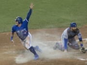 Toronto Blue Jays&#039; Josh Donaldson, left, celebrates after scoring on a throwing error from Texas Rangers second baseman Rougned Odor as Texas Rangers catcher Jonathan Lucroy kneels on the plate during tenth inning American League Division Series action, in Toronto on Sunday, Oct. 9, 2016.