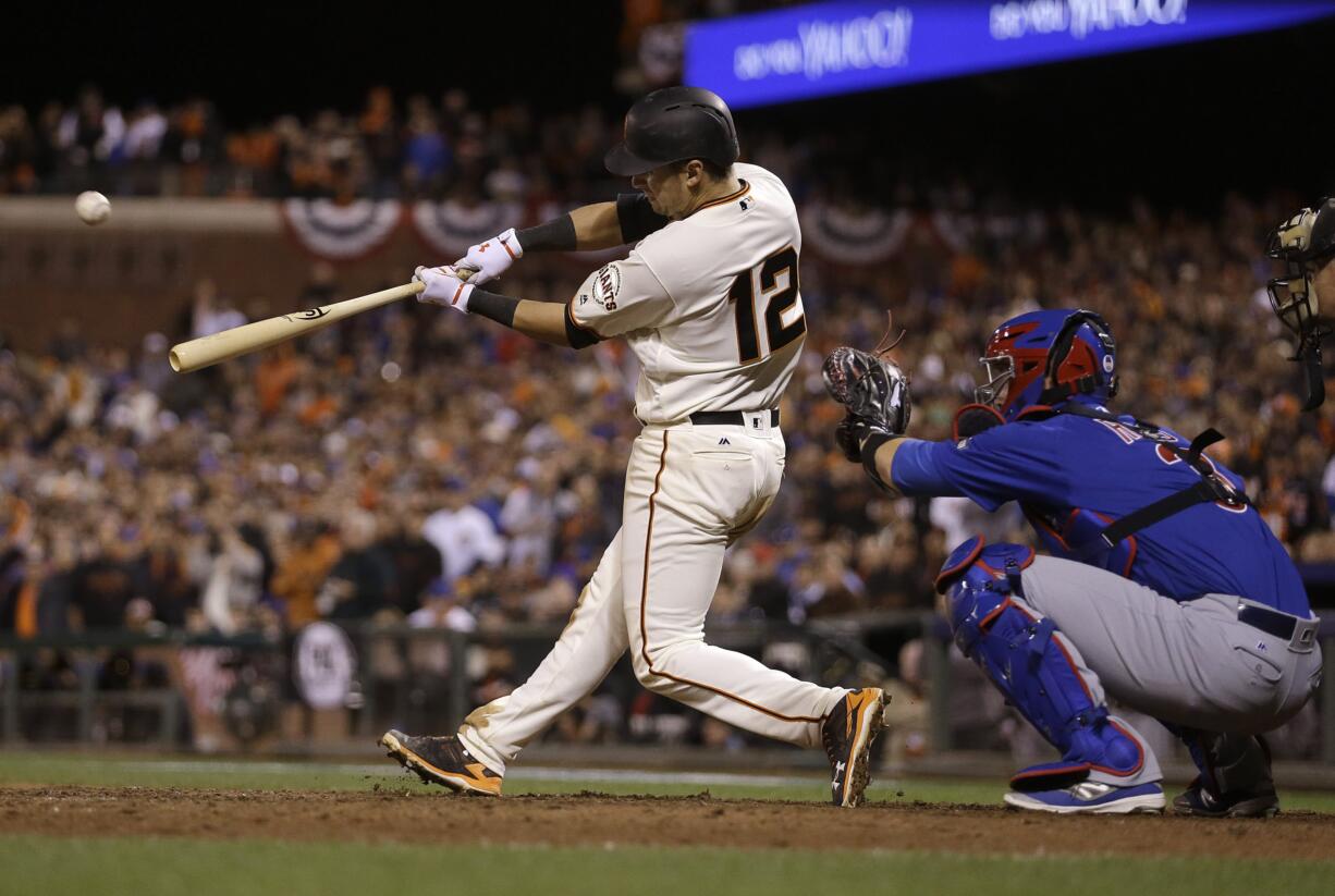 San Francisco Giants' Joe Panik (12) hits a double to score Brandon Crawford in front of Chicago Cubs catcher David Ross during the thirteenth inning of Game 3 of baseball's National League Division Series in San Francisco, Monday, Oct. 10, 2016. The Giants won 6-5 in 13 innings.