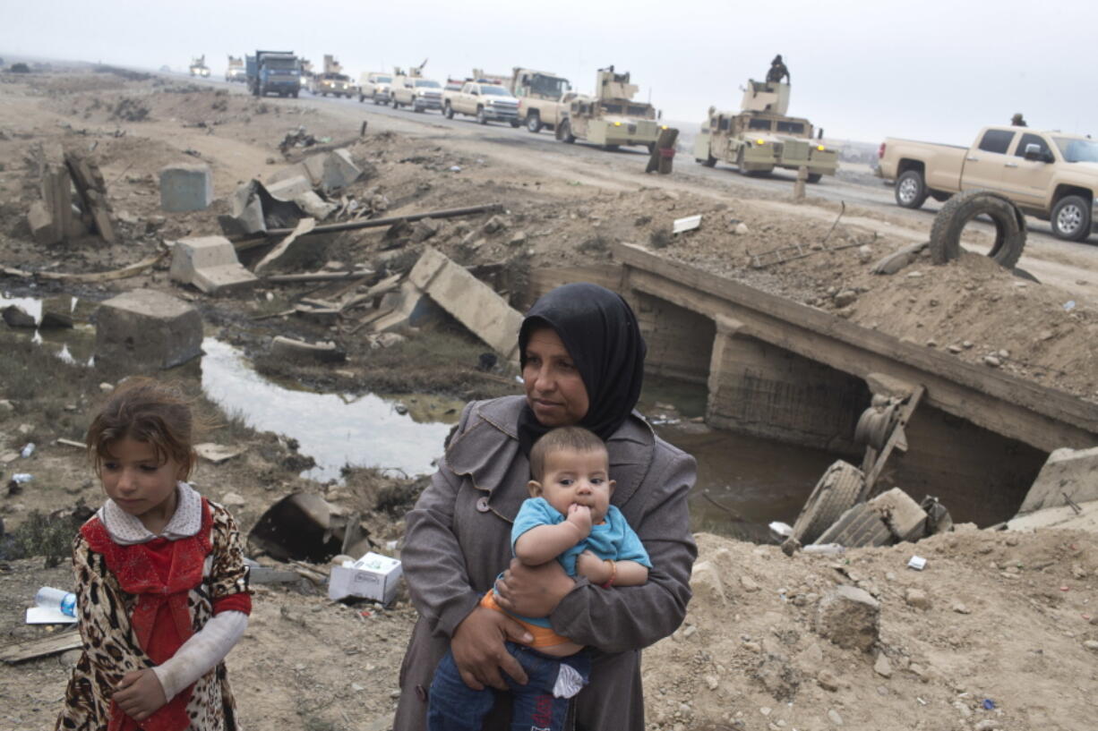 Internally displaced persons stand at a checkpoint Sunday as an Iraqi army convoy passes by in Qayyarah, about 31 miles south of Mosul, Iraq. The U.N. and aid organizations say some 5,000 civilians have been displaced during the operation to retake the city of Mosul.