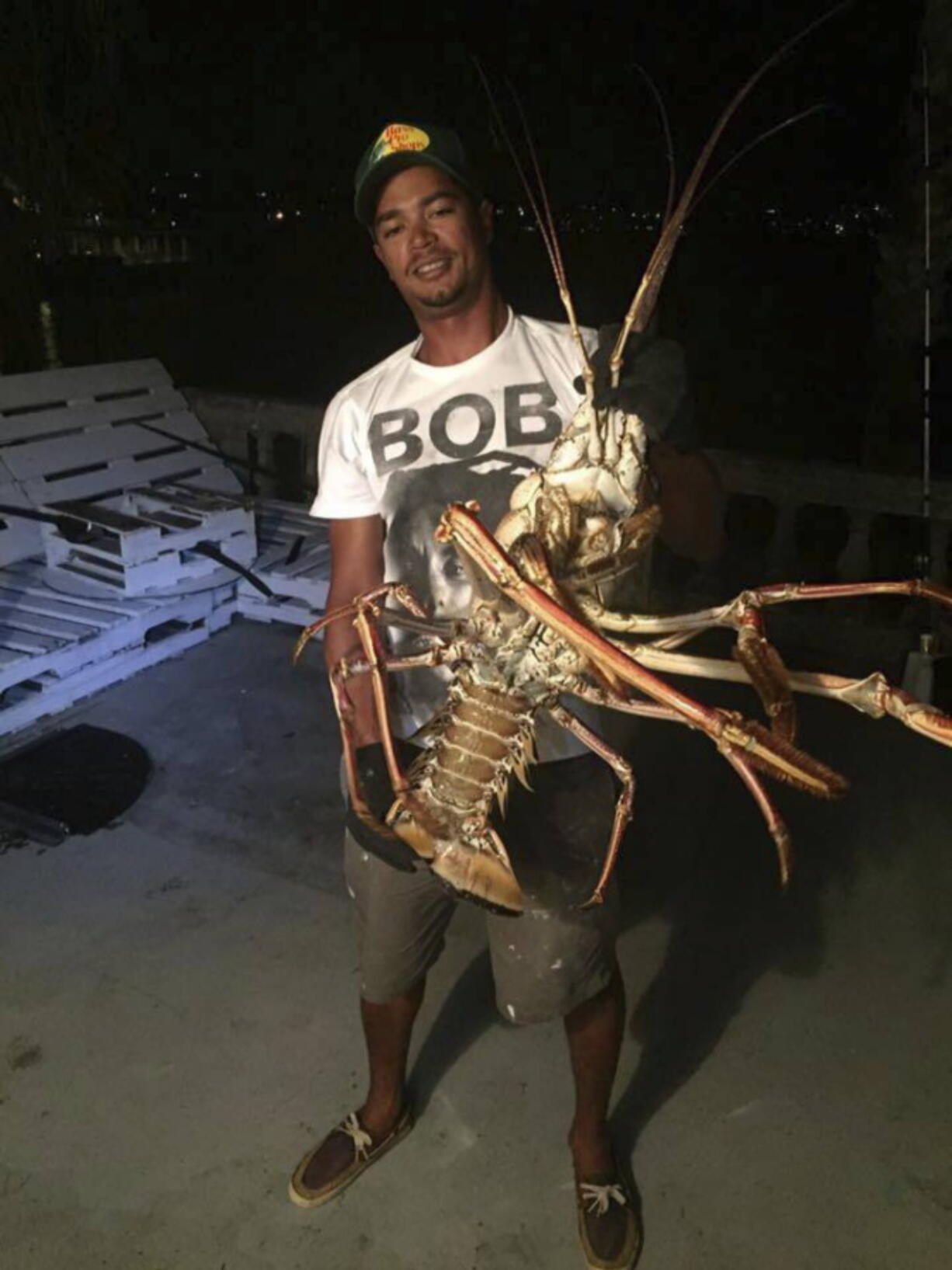 Tristan Loescher holds up a 14-pound spiny lobster he caught while fishing on Oct. 14, 2016, at an undisclosed shoreline location in Bermuda.