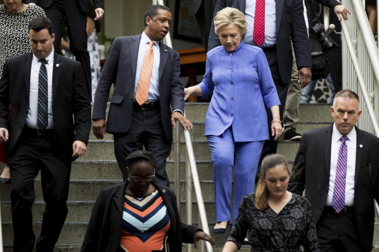 Democratic presidential candidate Hillary Clinton, right, speaks with Traveling Political Advisor Darren Peters, center left, as she leaves an early voting brunch Sunday at Fado Irish Pub in Miami.