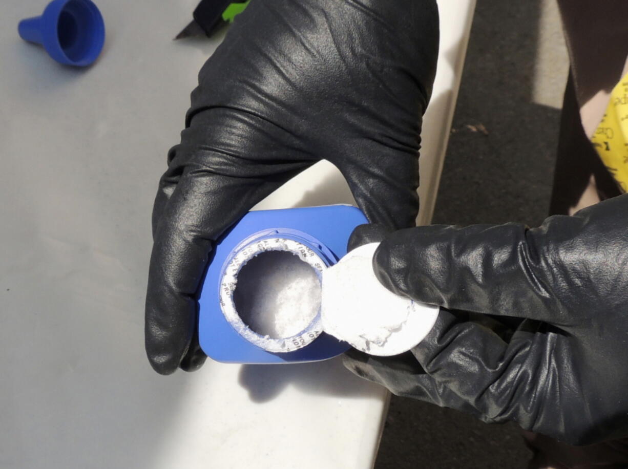 A member of the Royal Canadian Mounted Police opens a printer ink bottle in June in Vancouver, B.C., containing the opioid carfentanil, imported from China.