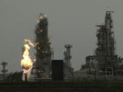 FILE - In this April 2, 2010, file photo, a  Tesoro Corp. refinery, including a gas flare flame that is part of normal plant operations, is shown in Anacortes, Wash. after a fatal overnight fire and explosion. (AP Photo/Ted S.
