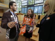 Dujie Tahat, left, hands out posters Sept. 21 to Marilyn Balcerak, right, and Rep. Tana Senn, D-Mercer Island, center, before a news conference in Bellevue, promoting Initiative 1491, which will be on the ballot in the November elections. (Ted S.