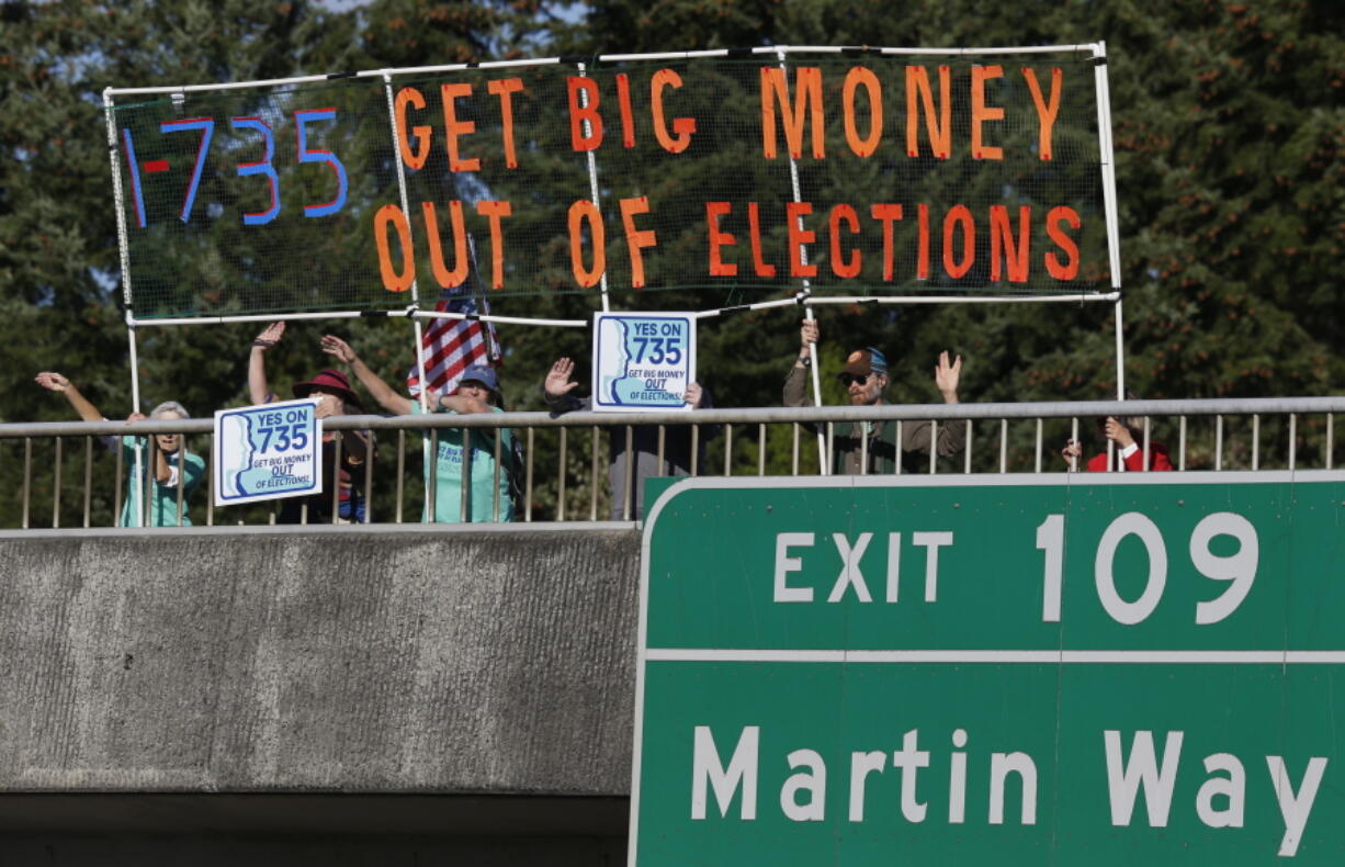 Supporters of Initiative 735 hold a banner Sept. 22 above Interstate 5 during the evening commute in Lacey. Proponents of the statewide ballot initiative want to get big money out of politics by backing a federal constitutional amendment that says free speech in the form of political contributions belongs to people, not corporations. Opponents of the measure say the government shouldn&#039;t limit the First Amendment. (AP Photo/Ted S.