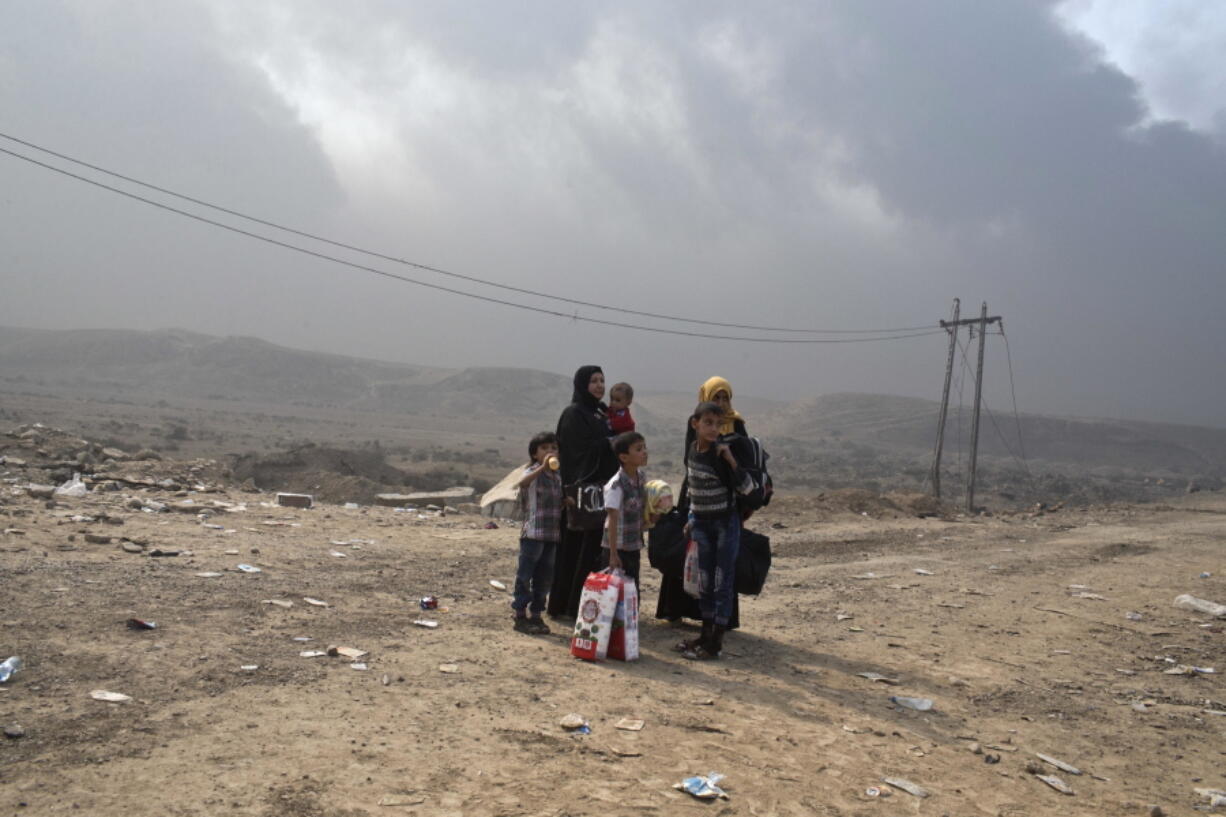 Displaced people wait for transport Wednesday at a checkpoint in Qayara, south of Mosul, Iraq. Islamic State militants were going door to door in farming communities south of Mosul, ordering people at gunpoint to follow them north to the city.