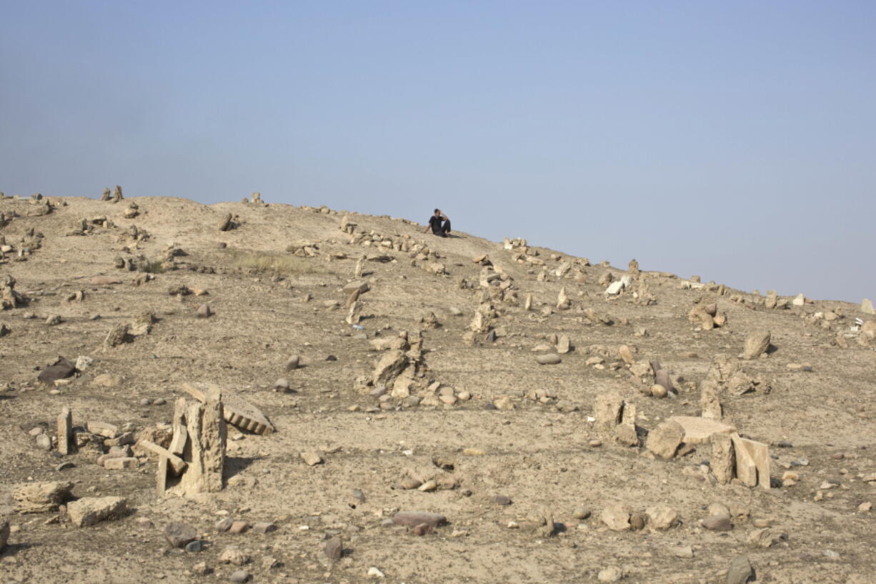 A man sits inside a graveyard damaged by Islamic State extremists in Qayara, some 31 miles, 50 km, south of Mosul, Iraq, on Thursday. When IS overran Qayara more than two years ago, the extremist group began destroying headstones at the local graveyard, telling residents they were forbidden because they did not exist at the time of the prophet.