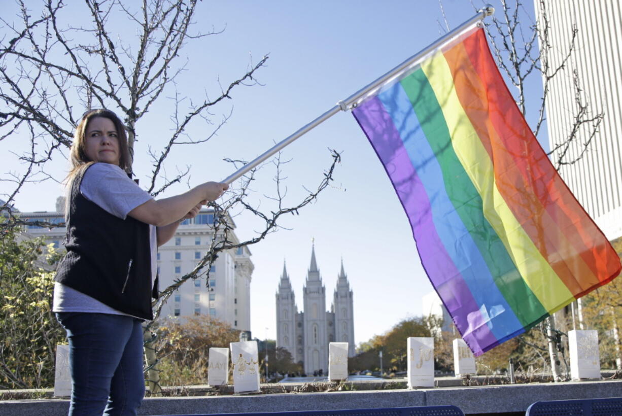 Sandy Newcomb poses with a rainbow flag as Mormons gather for a mass resignation from the Church of Jesus Christ of Latter-day Saints, in Salt Lake City on Nov. 14, 2015. Mormon leaders are telling gay and lesbian church members that attraction to people of the same sex is not a sin or a measure of their faithfulness.