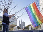 Sandy Newcomb poses with a rainbow flag as Mormons gather for a mass resignation from the Church of Jesus Christ of Latter-day Saints, in Salt Lake City on Nov. 14, 2015. Mormon leaders are telling gay and lesbian church members that attraction to people of the same sex is not a sin or a measure of their faithfulness.