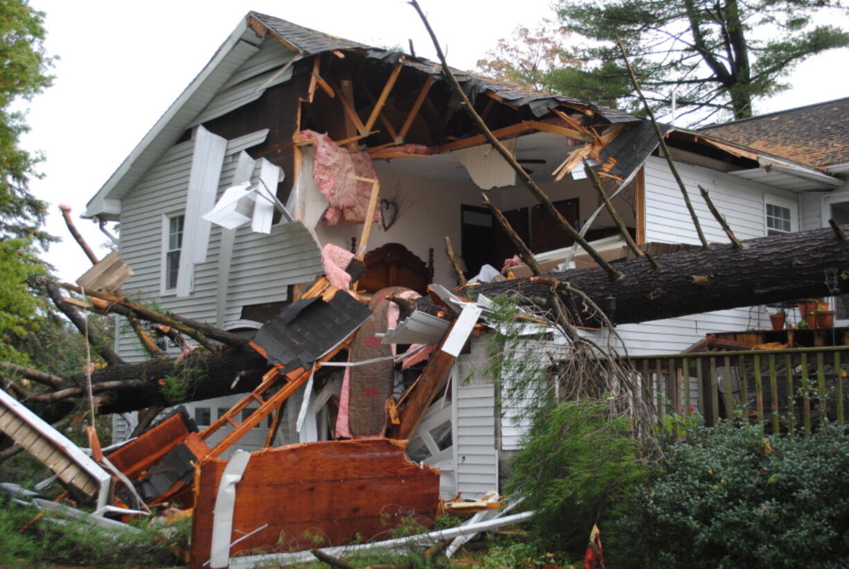 A large tree lays fallen on a house Friday after high winds and heavy rain hit the area and neighborhood, south of Lock Haven, in Clinton County, Pa. Homeowner Frank Dwyer, a well-known retired school teacher and former principal, died in the incident. A series of storms turned roads into rivers, closed schools and damaged hundreds of homes.