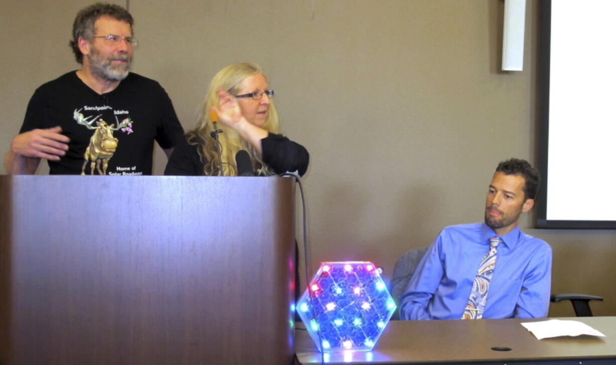 In this Sept. 30, 2016, photo, Solar Roadways founders Scott Brusaw, left, and Julie Brusaw display a one-third sized replica of one of their solar pavement panels at a news conference in Sandpoint, Idaho as Sandpoint mayor Shelby Rognstad looks on at right. Rognstad said the company is drawing visitors to the resort town. Solar Roadways recently unveiled its first public installation in a downtown plaza in the resort town of Sandpoint: about 150 square feet of hexagon-shaped solar panels that people can walk and bicycle on. (AP Photo/Nicholas K. Geranios) (Nicholas K.