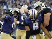 Washington wide receiver Dante Pettis (8) is greeted by teammates Darrell Daniels, left, and offensive lineman Jared Hilbers, right, after scoring a touchdown against Stanford in an NCAA college football game, Friday, Sept. 30, 2016, in Seattle. (AP Photo/Ted S.