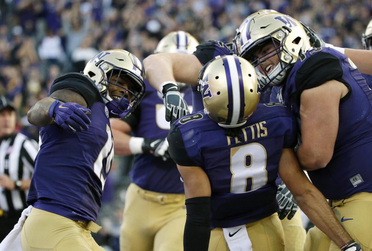 Washington wide receiver Dante Pettis (8) is greeted by teammates Darrell Daniels, left, and offensive lineman Jared Hilbers, right, after scoring a touchdown against Stanford in an NCAA college football game, Friday, Sept. 30, 2016, in Seattle. (AP Photo/Ted S.