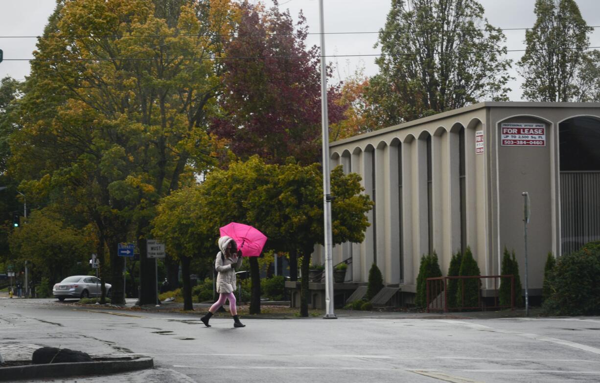 Wind overwhelms a pedestrian's umbrella as she crosses Main Street in downtown Vancouver on Friday morning.