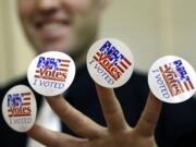 Seth Schaecher, a deputy election official, displays stickers that he gives to voters, Tuesday, Nov. 8, 2016, at a polling place in Exeter, N.H.