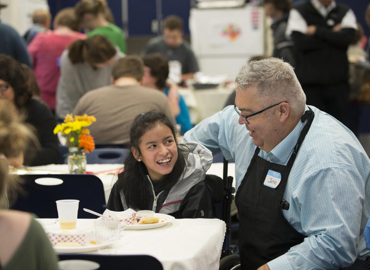 Hockinson Middle School seventh-grader Jenna Coulimore, 12, center, is all smiles along with Hockinson High School teacher John Frank as they enjoy a Thanksgiving feast organized by the high school&#039;s developmental resource room students.