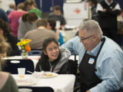 Hockinson Middle School seventh-grader Jenna Coulimore, 12, center, is all smiles along with Hockinson High School teacher John Frank as they enjoy a Thanksgiving feast organized by the high school&#039;s developmental resource room students.