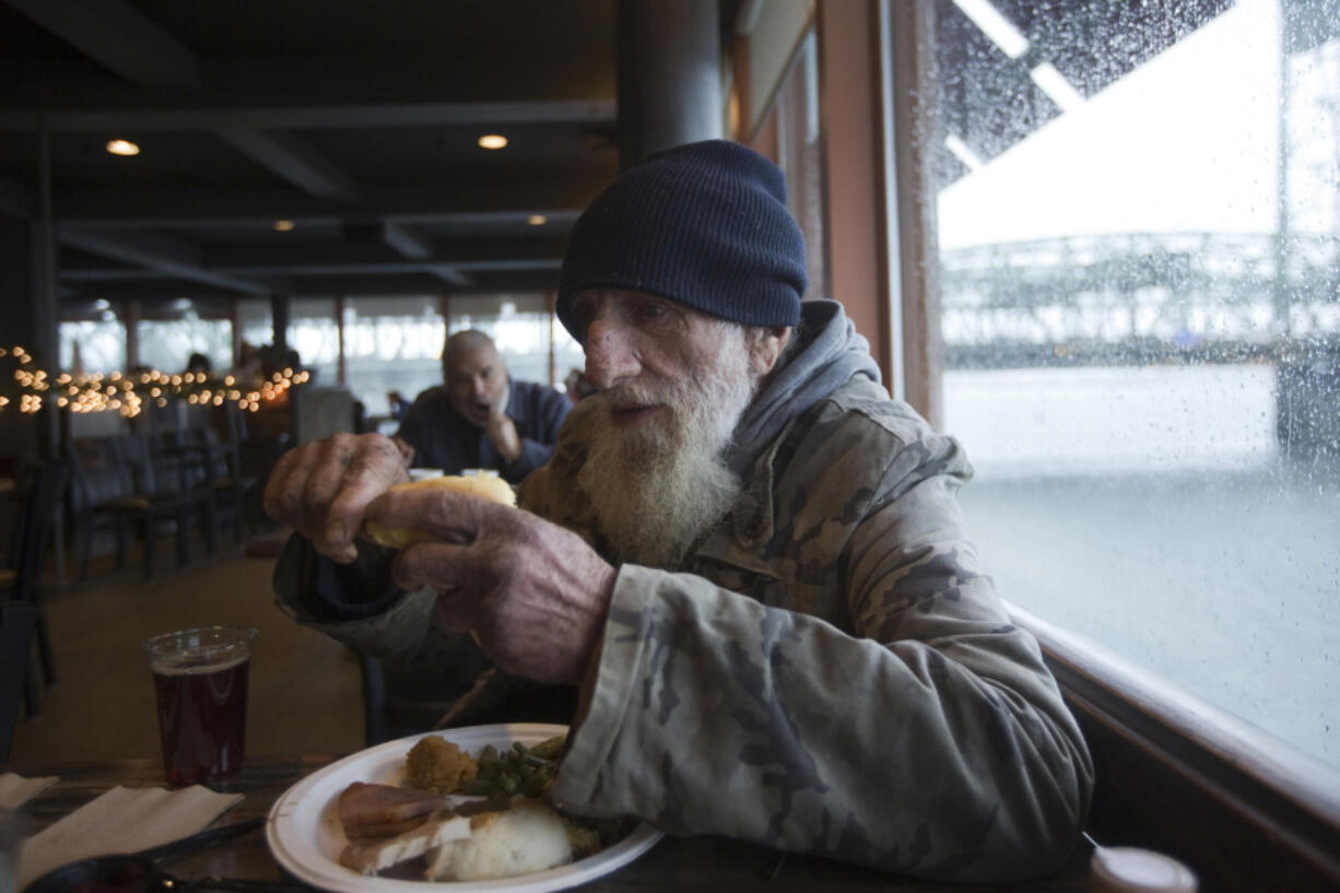 Homeless veteran Joe Mazzel, 69, butters a roll as he enjoys a free Thanksgiving meal Thursday at WareHouse &#039;23 in Vancouver. After a one-year hiatus, organizers of the popular event have revived the long-standing tradition to once again serve those in need.