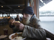 Homeless veteran Joe Mazzel, 69, butters a roll as he enjoys a free Thanksgiving meal Thursday at WareHouse &#039;23 in Vancouver. After a one-year hiatus, organizers of the popular event have revived the long-standing tradition to once again serve those in need.