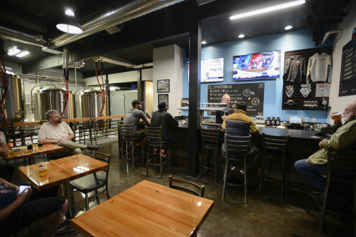 Customers enjoy drinks at Victor 23 Brewing in Vancouver on Tuesday. The brewpub serves food Wednesday through Sunday.