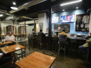 Customers enjoy drinks at Victor 23 Brewing in Vancouver on Tuesday. The brewpub serves food Wednesday through Sunday.