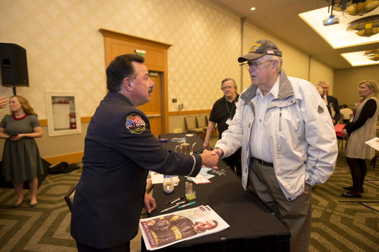 Retired New York Fire Department Lt. Joe Torrillo, left, greets Vietnam War veteran Bill Peden while signing posters after his speech at the Hilton Vancouver Washington on Thursday.