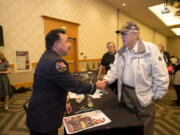 Retired New York Fire Department Lt. Joe Torrillo, left, greets Vietnam War veteran Bill Peden while signing posters after his speech at the Hilton Vancouver Washington on Thursday.