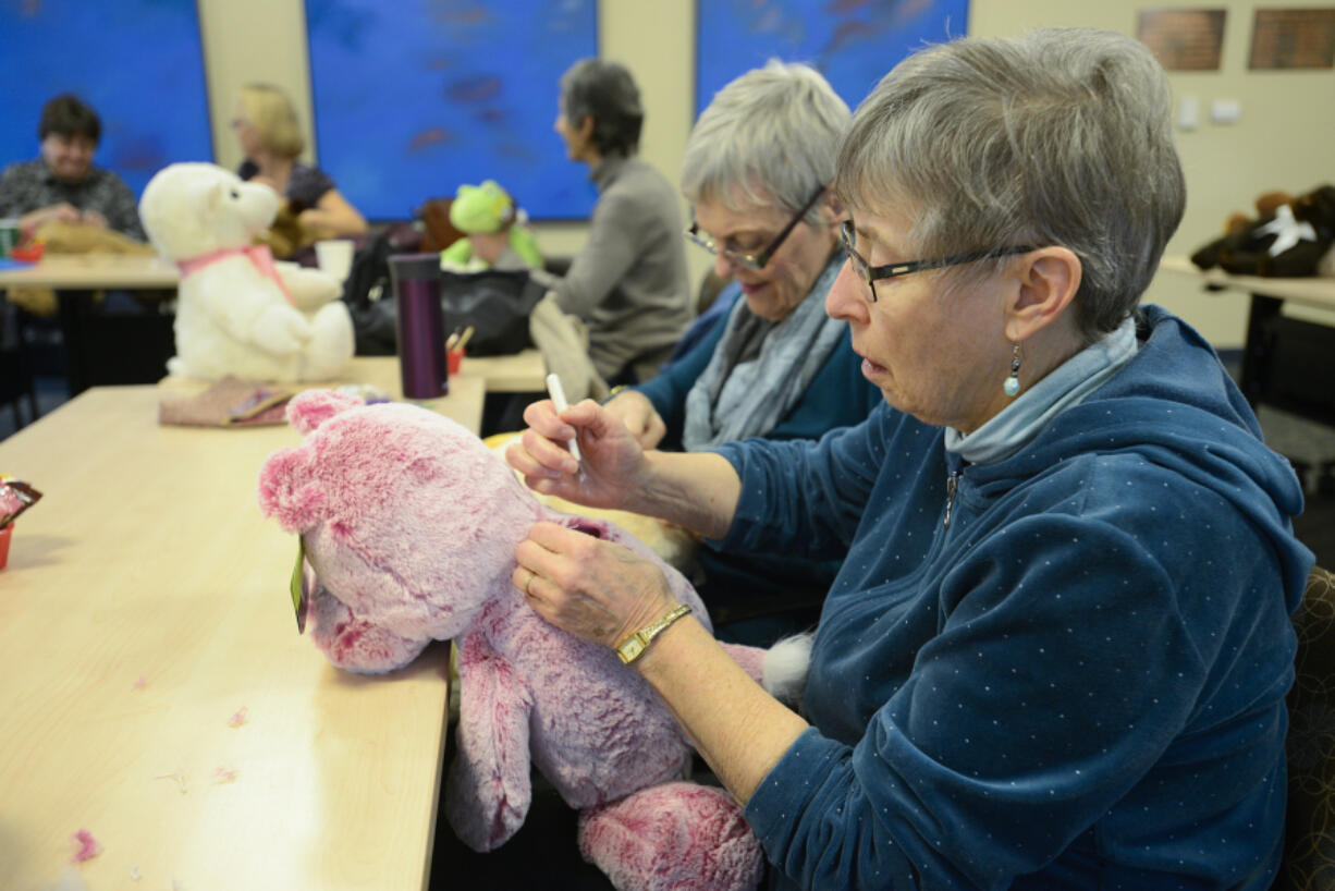 Donna Shaver tears the seam on a stuffed teddy bear in order to insert a small bag of rocks. Volunteers from the Unitarian Universalist Church of Vancouver created weighted stuffed animals for clients at the Children&#039;s Center.
