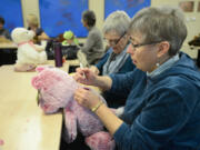 Donna Shaver tears the seam on a stuffed teddy bear in order to insert a small bag of rocks. Volunteers from the Unitarian Universalist Church of Vancouver created weighted stuffed animals for clients at the Children&#039;s Center.