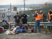 Officer Greg Zimmerman, second from left, talks with a camper as cleanup crews clear the area in downtown Vancouver on Thursday morning.