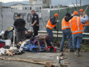 Officer Greg Zimmerman, second from left, talks with a camper as cleanup crews clear the area in downtown Vancouver on Thursday morning.