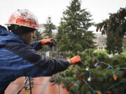 Cody Taplin, a window technician at St. Mary&#039;s Services in Vancouver, hangs Christmas lights on a tree from a cherry picker at Esther Short Park in downtown Vancouver on Wednesday.