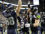 Seattle Seahawks quarterback Russell Wilson, center, celebrates with tight end Jimmy Graham (88) and offensive guard Mark Glowinski, right, after Wilson passed to Graham for a touchdown against the Buffalo Bills in the first half of an NFL football game, Monday, Nov. 7, 2016, in Seattle.