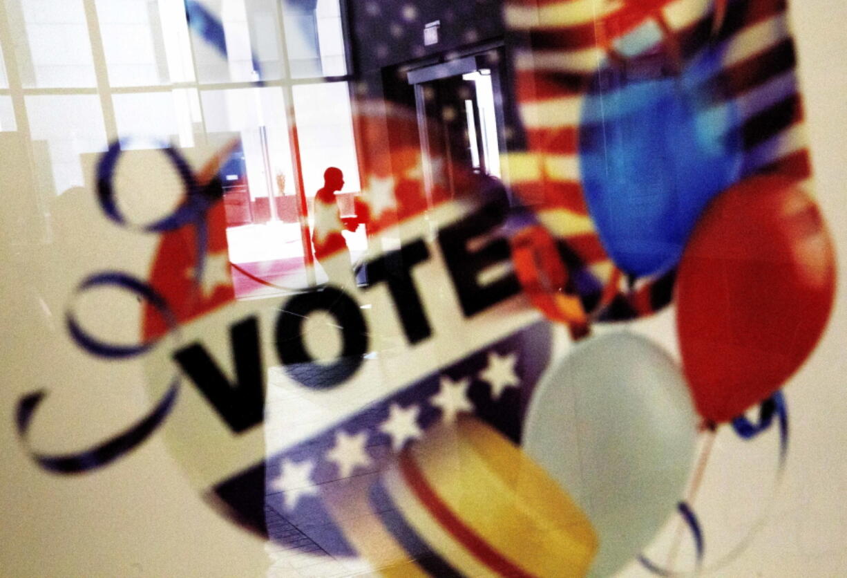 A voter is reflected in the glass frame of a poster while leaving a polling site in Atlanta on Nov. 1 during early voting.