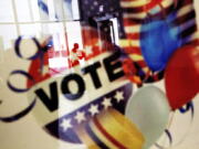 A voter is reflected in the glass frame of a poster while leaving a polling site in Atlanta on Nov. 1 during early voting.