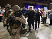 A man, at background center with blue sweater, is escorted by law enforcement officers moments after Republican presidential candidate Donald Trump was rushed offstage by Secret Service agents during a campaign rally in Reno, Nev., on Saturday, Nov. 5, 2016.