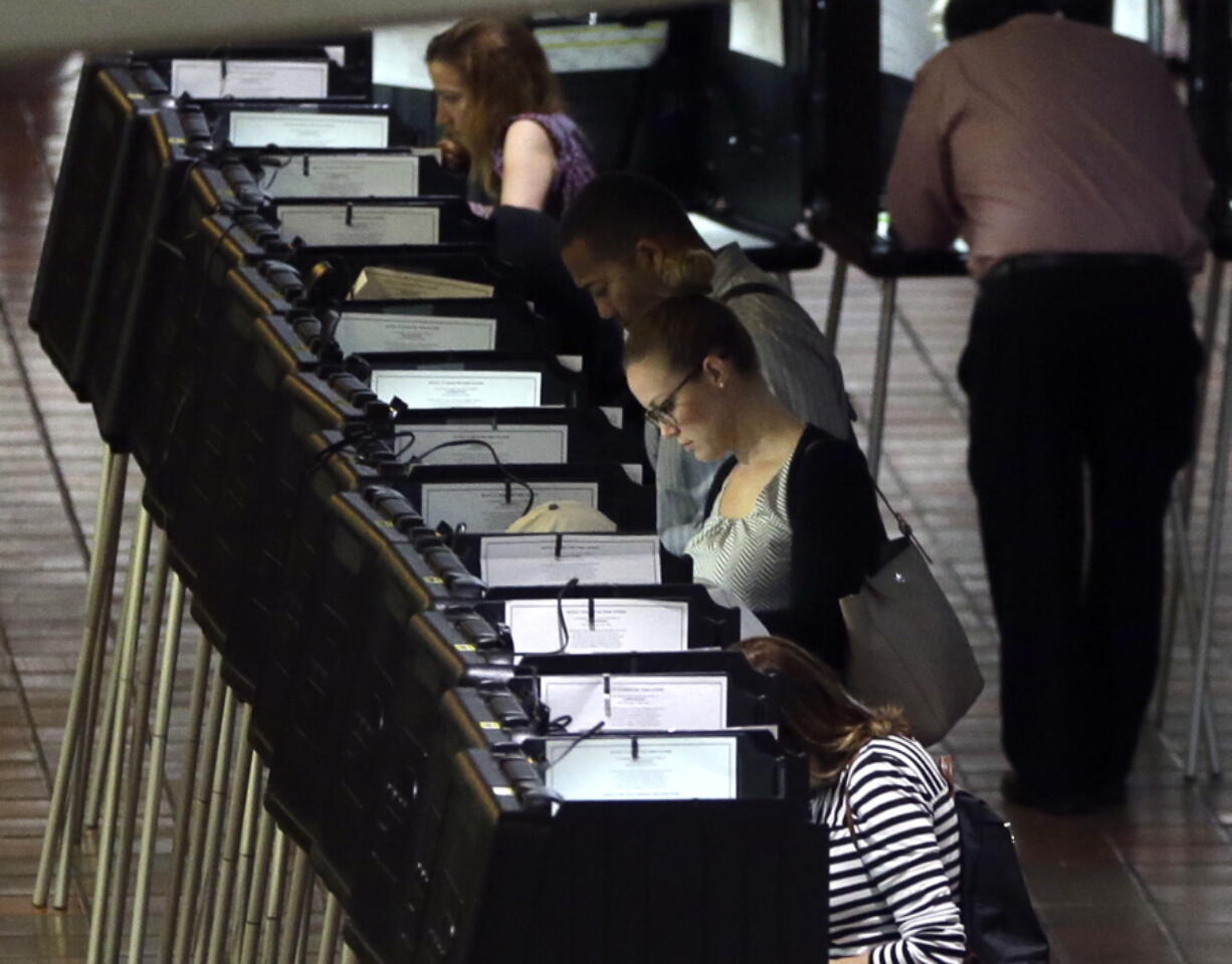 People vote at a polling station on the first day of early voting in Miami-Dade County for the general election Monday in Miami.