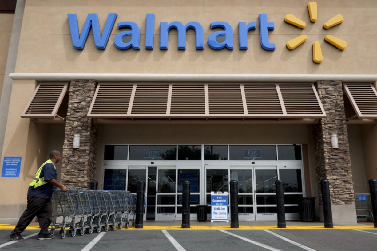 A worker pushes shopping carts in front of a Wal-Mart store in La Habra, Calif. (Jae C.