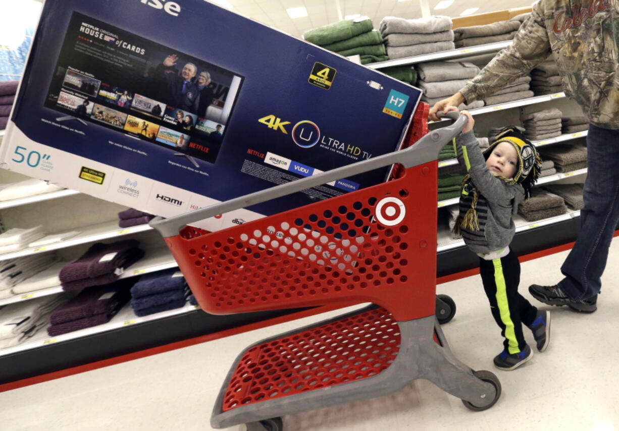 Hunter Harvey, 2, helps his dad, C.J., wheel a big screen TV at Target on Black Friday in Wilmington, Mass.