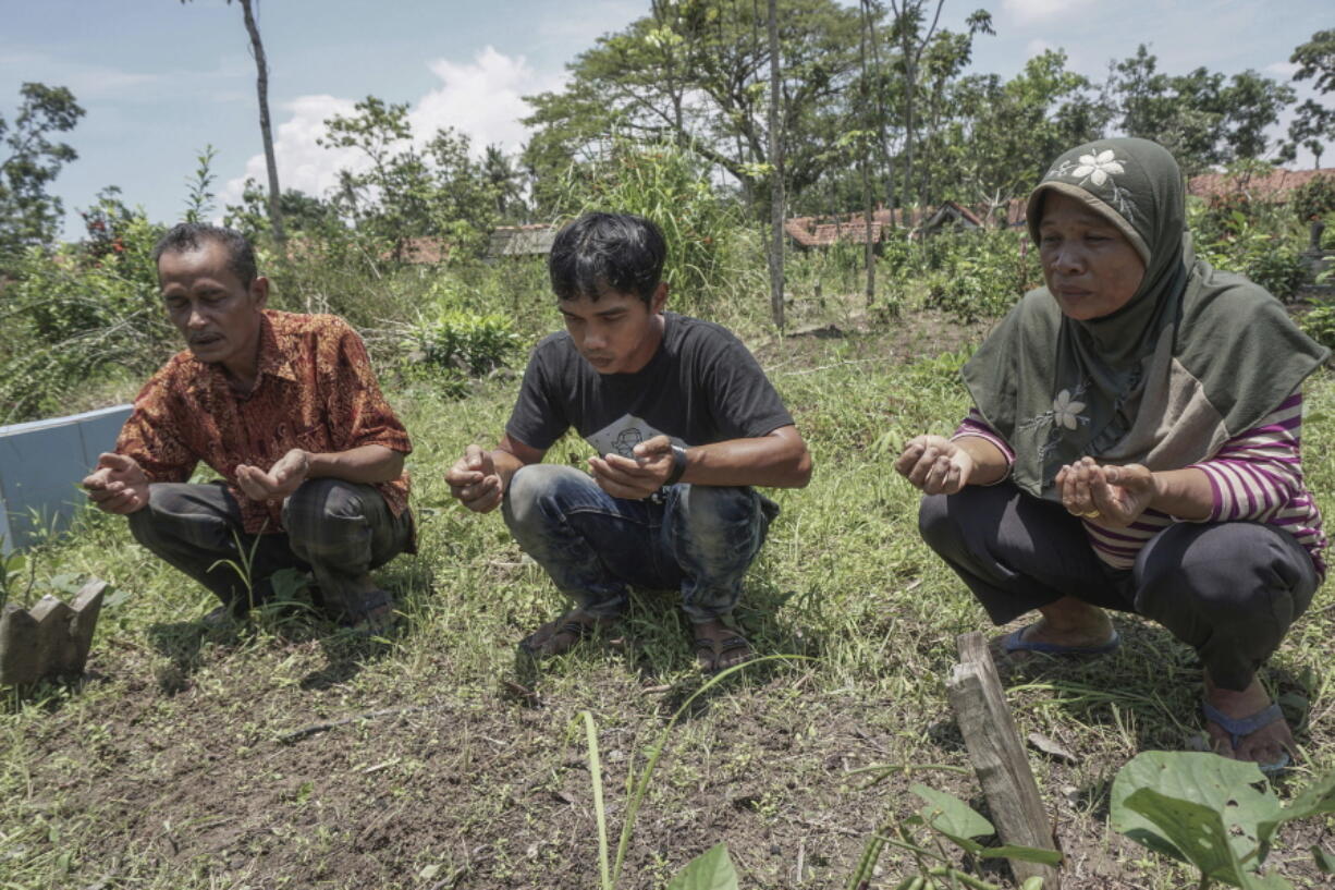 Family members of Indonesian migrant worker Sumarti Ningsih who was murdered in Hong Kong, from left to right; father Ahmad Kaliman, brother Suyit and mother Suratmi pray at her grave in Cilacap, Central Java, Indonesia. The Hong Kong trial of a British stock trader who murdered two Indonesian women and horrifically tortured one of them, recording the three-day ordeal on his phone, has barely registered in the victims&#039; home country, let alone elicited shock or sympathy.