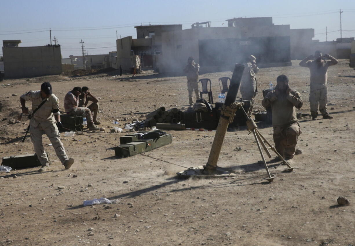 Iraqi soldiers cover their ears during a mortar shelling against Islamic State militants, in the Samah front line neighborhood, in Mosul, Iraq, on Friday.