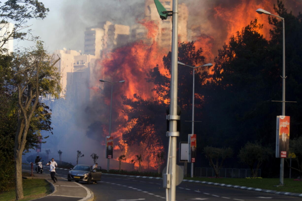 People run Thursday as wildfires rages in Haifa, Israel.