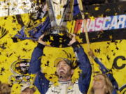 Jimmie Johnson lifts the trophy as he celebrates the NASCAR Sprint Cup auto race and series title, Sunday, Nov. 20, 2016, in Homestead, Fla.