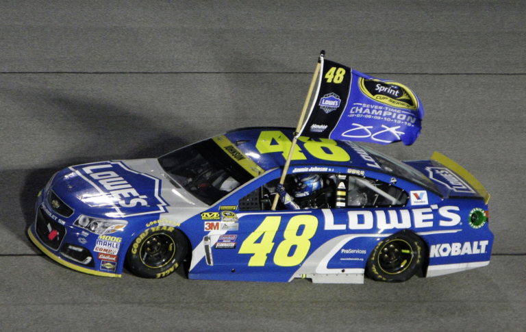 Jimmie Johnson hold his flag as he does the victory lap after wining the NASCAR Sprint Cup auto race and season title Sunday, Nov. 20, 2016, in Homestead, Fla.