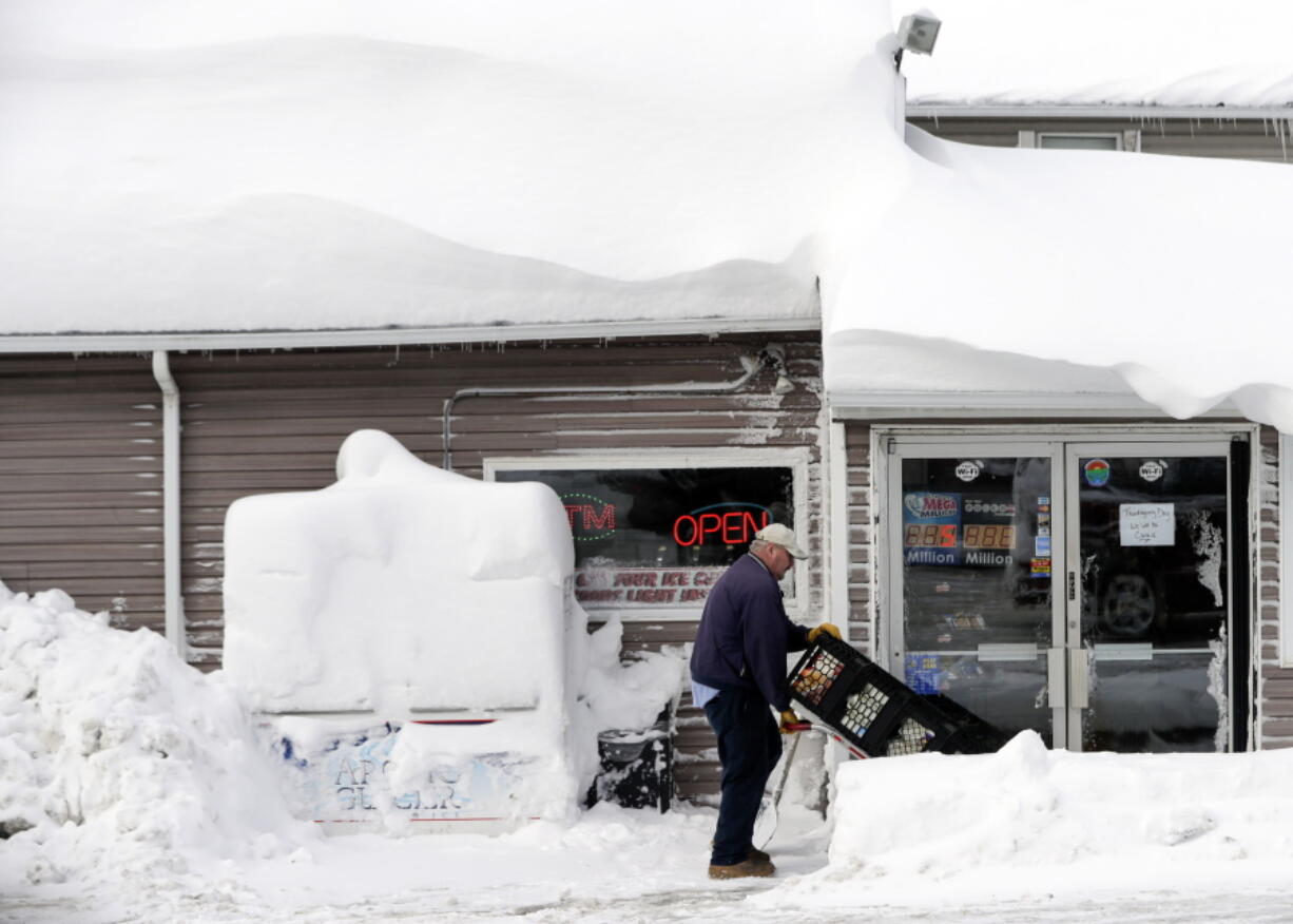 Bob Fox delivers milk to Grafton&#039;s Town Store, as he walks through lake-effect snow on the ground Monday in Grafton, N.Y.