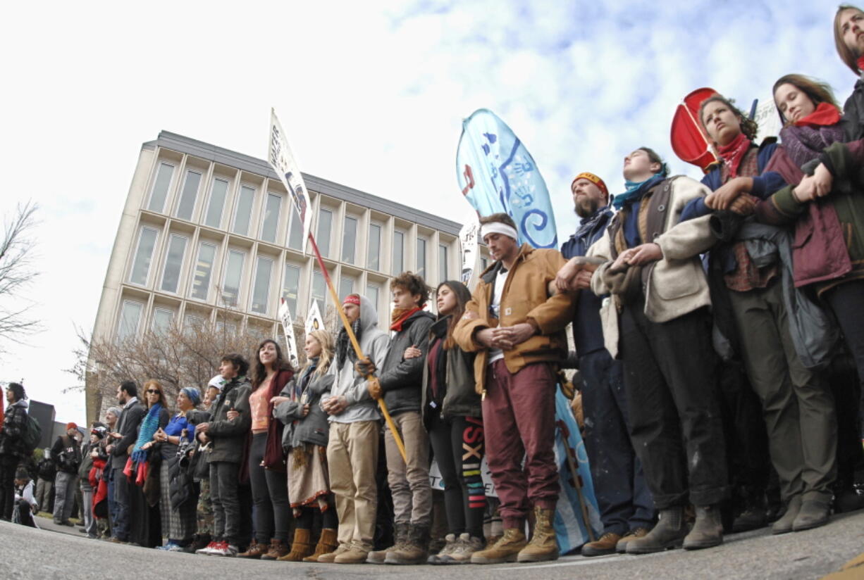 Dakota Pipeline protesters stand arm-in-arm at the intersection of Rosser Avenue and Fourth Street in downtown Bismarck, N.D., after marching from the state Capitol to the William L. Guy Federal Building on Monday.