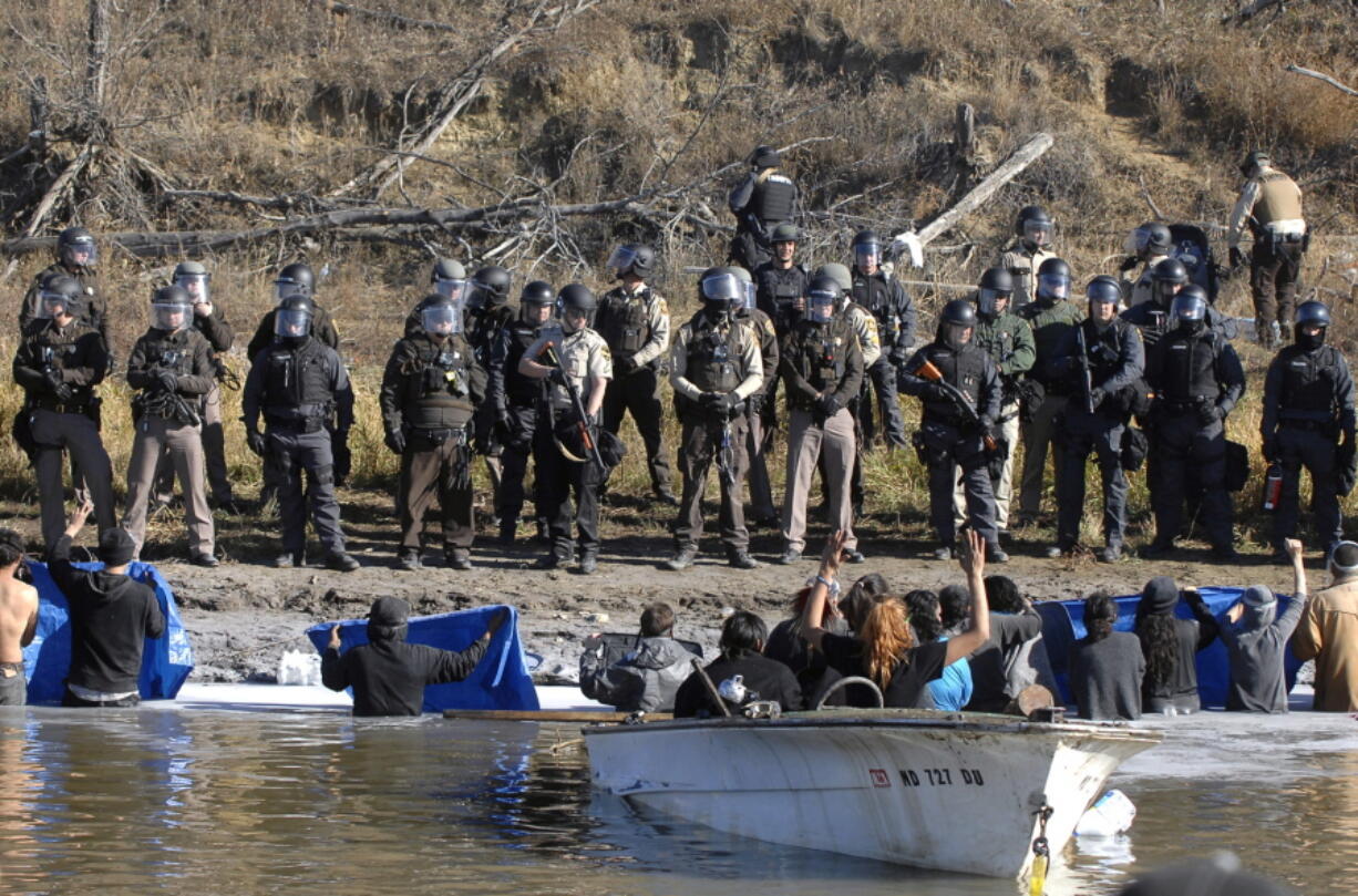 Dakota Access Pipeline protesters stand waist deep in the Cantapeta Creek, northeast of the Oceti Sakowin Camp, near Cannon Ball, N.D., on Wednesday. Officers in riot gear clashed again Wednesday with protesters near the Dakota Access pipeline, hitting dozens with pepper spray as they waded through waist-deep water in an attempt to reach property owned by the pipeline&#039;s developer.