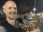 Detective Travis Fields of the Portland Police Bureau helps return Falke the Bengal cat to his owner Wednesday night. Fields was assisted by the Clark County Sheriff's Office in retrieving the stolen kitty from Brush Prairie.