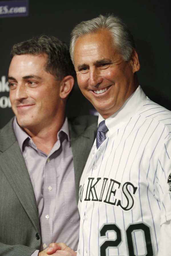 Newly named Colorado Rockies manager Bud Black, right, poses for photographers after pulling on his new jersey along with general manager Jeff Bridich during a news conference to introduce Black as the new skipper on Monday, Nov. 7, 2016, in Denver. Black succeeds Walt Weiss, who left after four seasons as manager at the conclusion of the regular season.